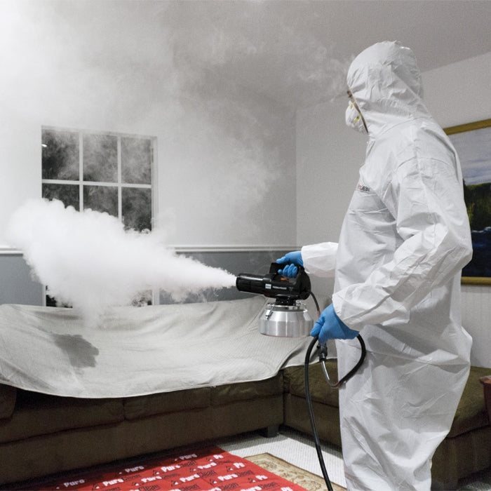 Technician in hazmat suit using fogging machine to treat mold in home