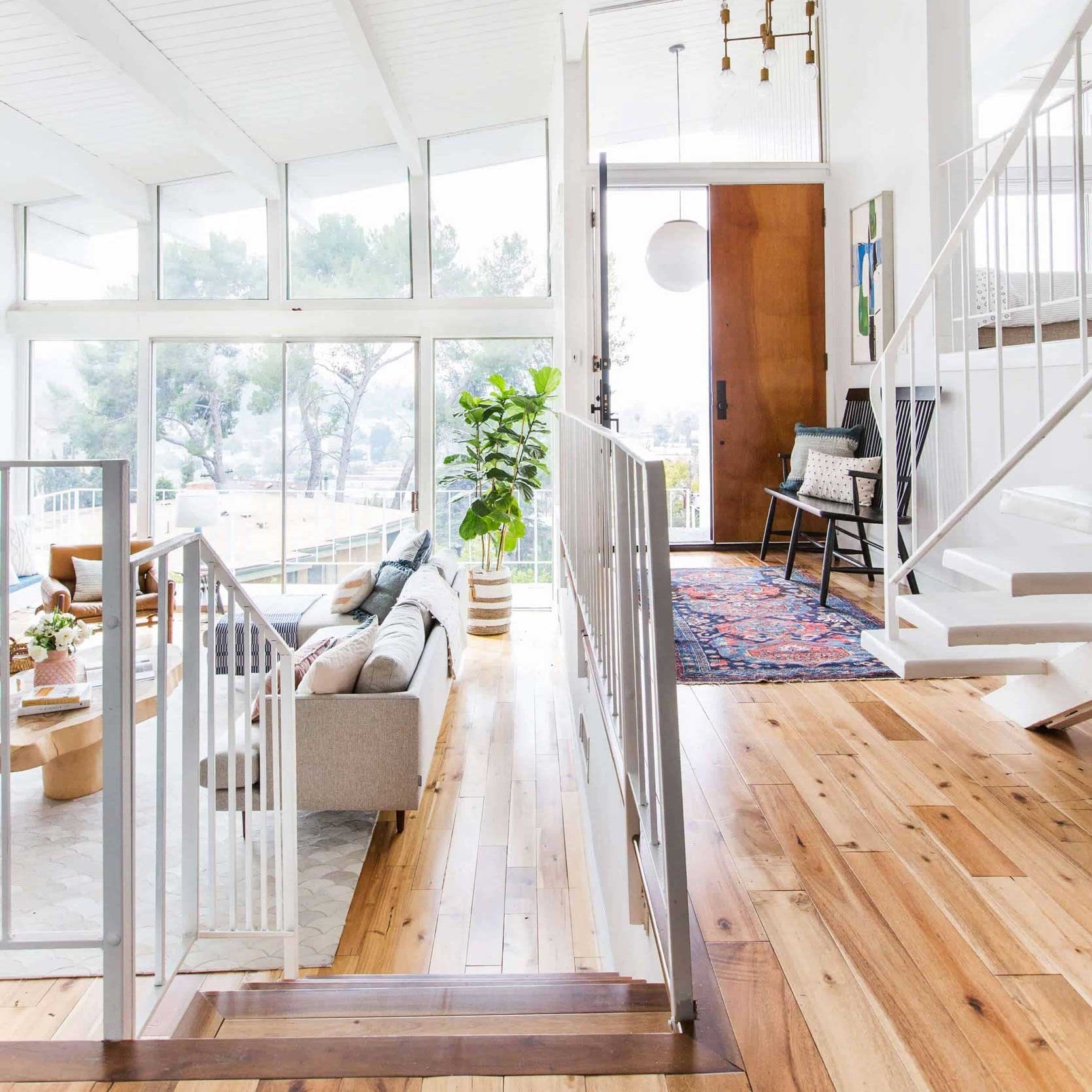 Bright home entryway with open stairway and living area, showing natural airflow between connected indoor spaces.